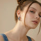 Woman wearing silver hoop earring with blue gemstone details, close-up