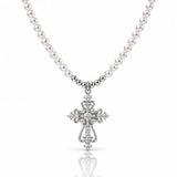 A silver cross pendant necklace with a strand of white pearls, featuring clear gemstones set into the cross and along the chain, shown on a white background with a soft reflection below.