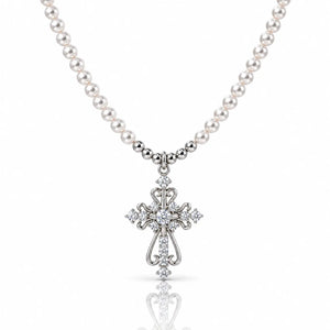 A silver cross pendant necklace with a strand of white pearls, featuring clear gemstones set into the cross and along the chain, shown on a white background with a soft reflection below.
