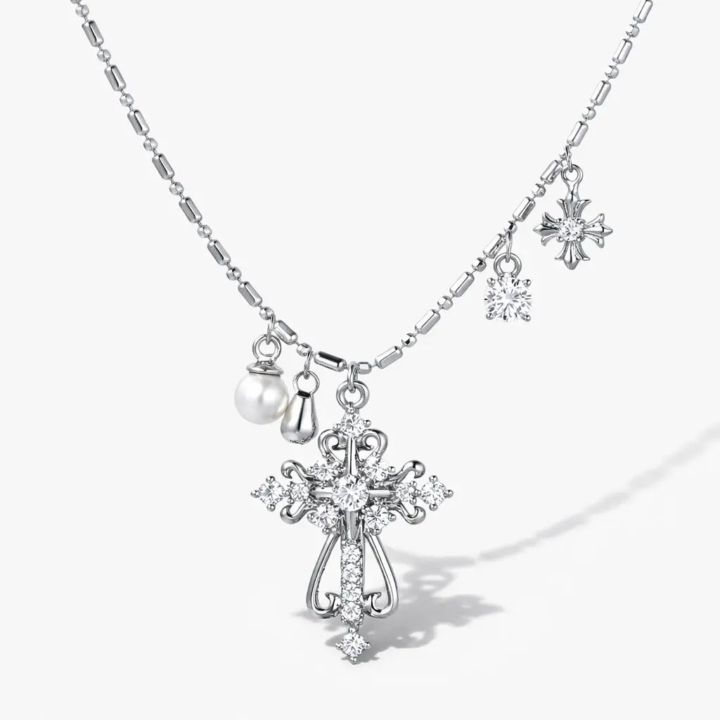 Layered silver necklace with crystal cross and pearl charms on a white background