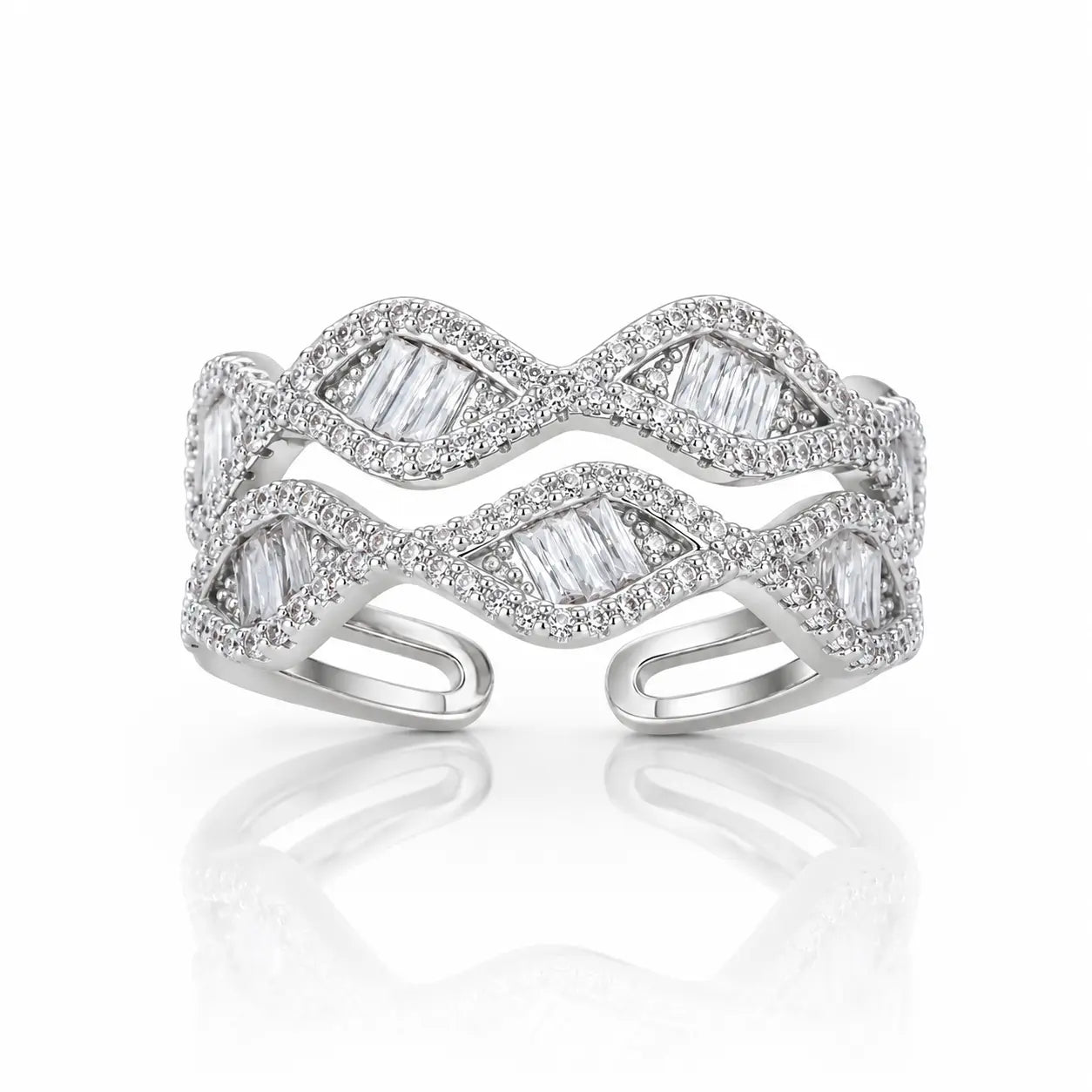 A silver-toned open cuff ring featuring a wavy, layered design paved with small clear stones and accented with larger baguette-cut clear stones, shown on a white background with a soft reflection.