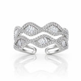 A silver-toned open cuff ring featuring a wavy, layered design paved with small clear stones and accented with larger baguette-cut clear stones, shown on a white background with a soft reflection.