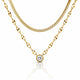 A gold necklace set featuring a double-layered chain design: a thinner snake chain and a thicker oval-link chain with a round bezel-set clear gemstone pendant, displayed on a white background with a soft reflection.