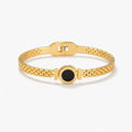 Gold bracelet with black mother of pearl center and Roman numeral engraving on white background
