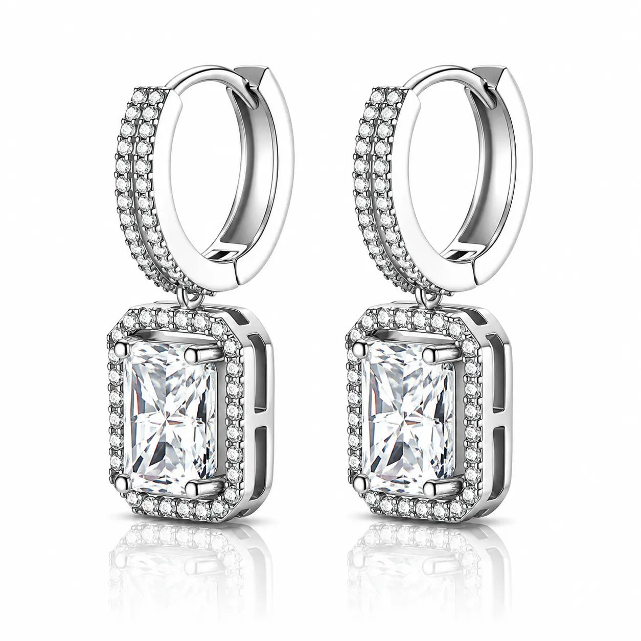 A pair of silver-toned huggie hoop earrings with rectangular emerald-cut clear gemstones surrounded by small pavé-set stones, shown on a clean white background with a soft reflection below.