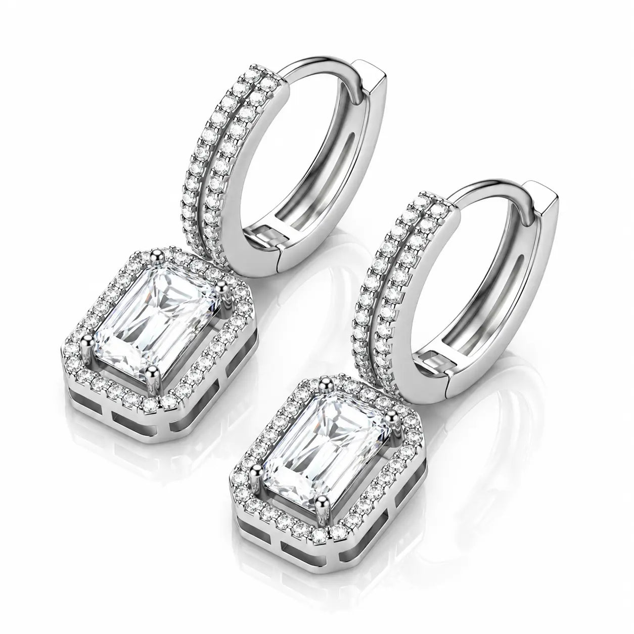 A pair of silver-toned huggie hoop earrings with rectangular emerald-cut clear stones and halo accents, displayed on a clean white background with a soft reflection.