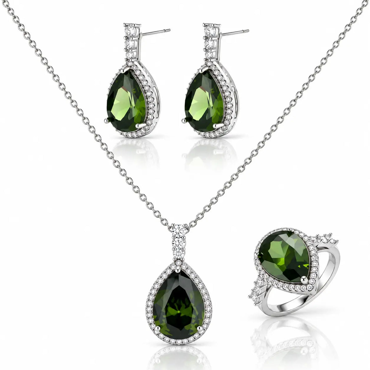 A three-piece silver jewelry set featuring a teardrop pendant necklace, matching drop earrings, and a ring, all adorned with dark green faceted gemstones and clear accent stones, displayed on a white reflective background.