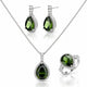 A three-piece silver jewelry set featuring a teardrop pendant necklace, matching drop earrings, and a ring, all adorned with dark green faceted gemstones and clear accent stones, displayed on a white reflective background.