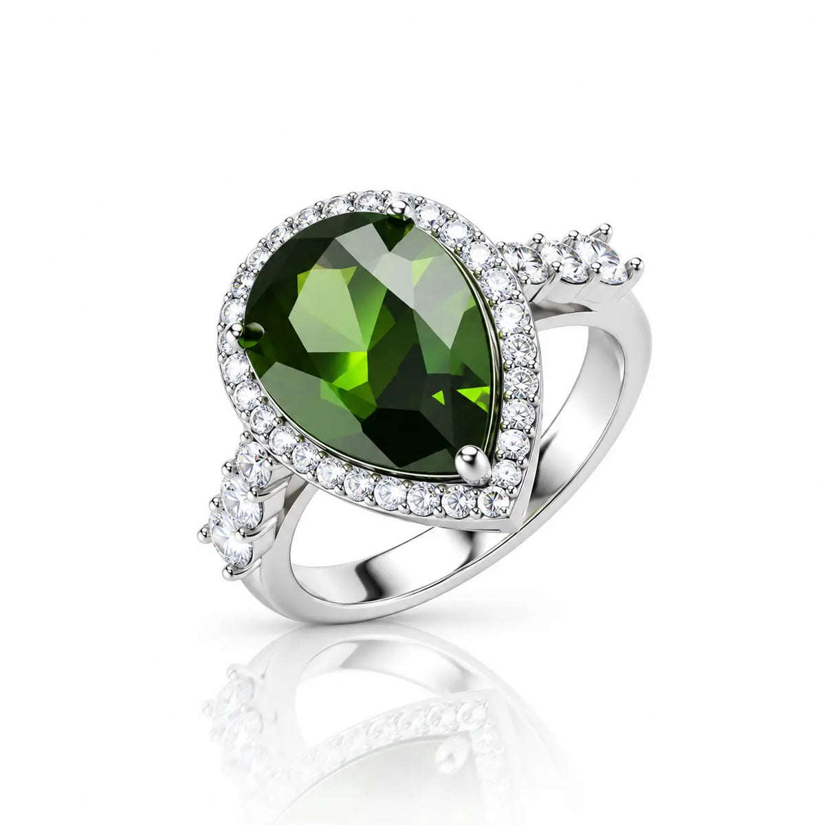 A silver ring featuring a large pear-cut green gemstone surrounded by a halo of small clear stones, with additional clear stones along the band, shown on a white background with a soft reflection.