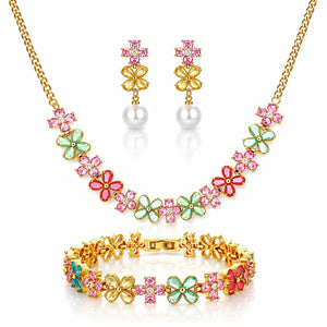 Gold-tone jewelry set featuring a necklace, matching drop earrings, and bracelet, decorated with pink and green flower-shaped rhinestones and white pearl-like beads.