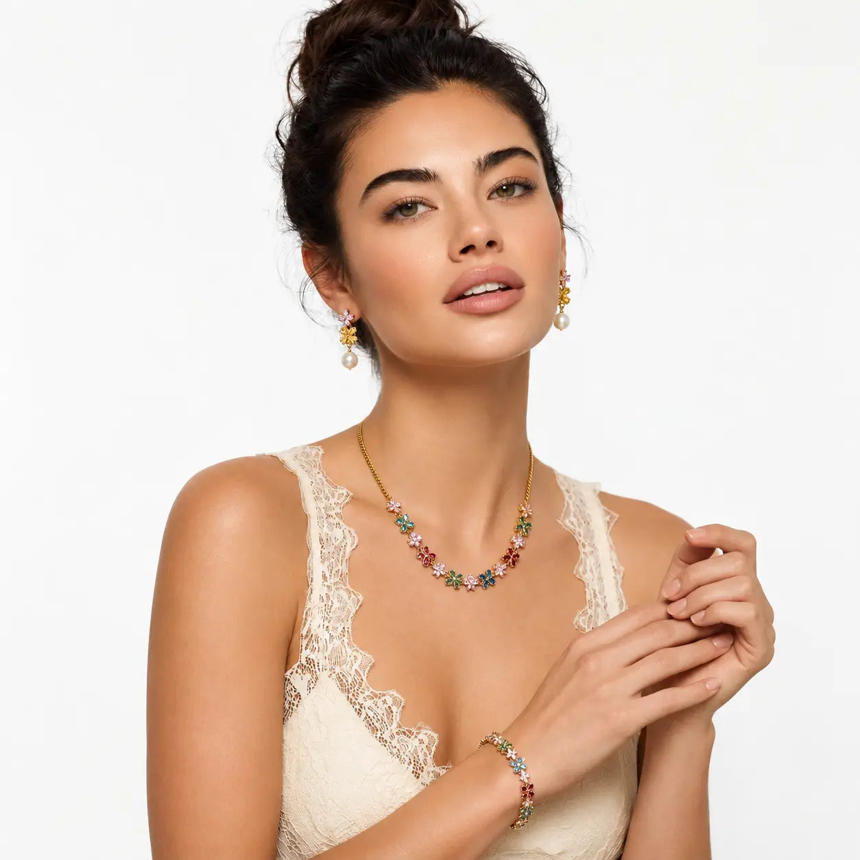 A woman wearing a gold necklace and matching earrings with colorful gemstone accents, paired with a matching bracelet, set against a plain white background.