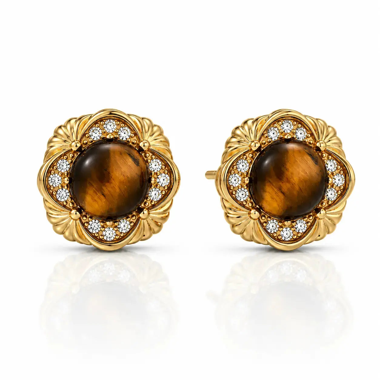 A pair of gold round stud earrings featuring a central brown tiger's eye stone surrounded by a halo of small clear stones, set in an ornate floral gold frame, on a white background with a soft reflection.