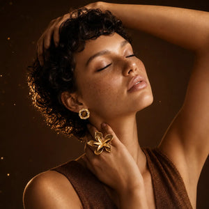 Woman wearing gold earrings against a warm brown background