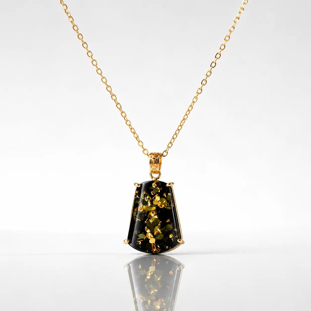 Gold necklace with a pendant featuring green gemstone on a white background