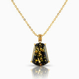 Gold necklace with a black pendant on a white background