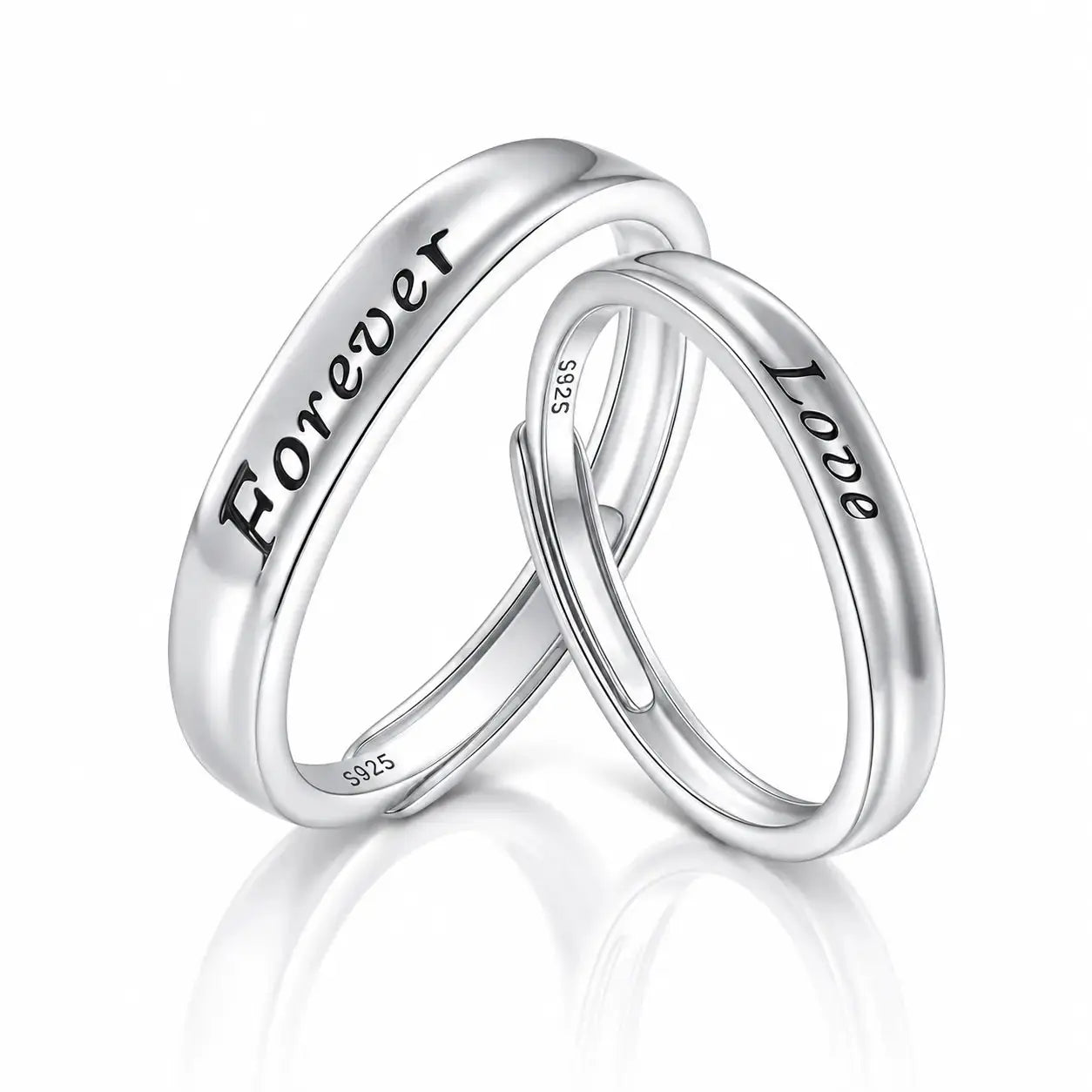 Two polished silver wedding bands interlocking on a reflective white surface. One band is engraved with the word 'Forever' and the other with 'Love'.