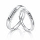 Two polished silver wedding bands interlocking on a reflective white surface. One band is engraved with the word 'Forever' and the other with 'Love'.