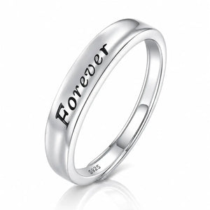 A polished silver band ring engraved with the word 'Forever' in black script, shown on a clean white background with a soft reflection below.