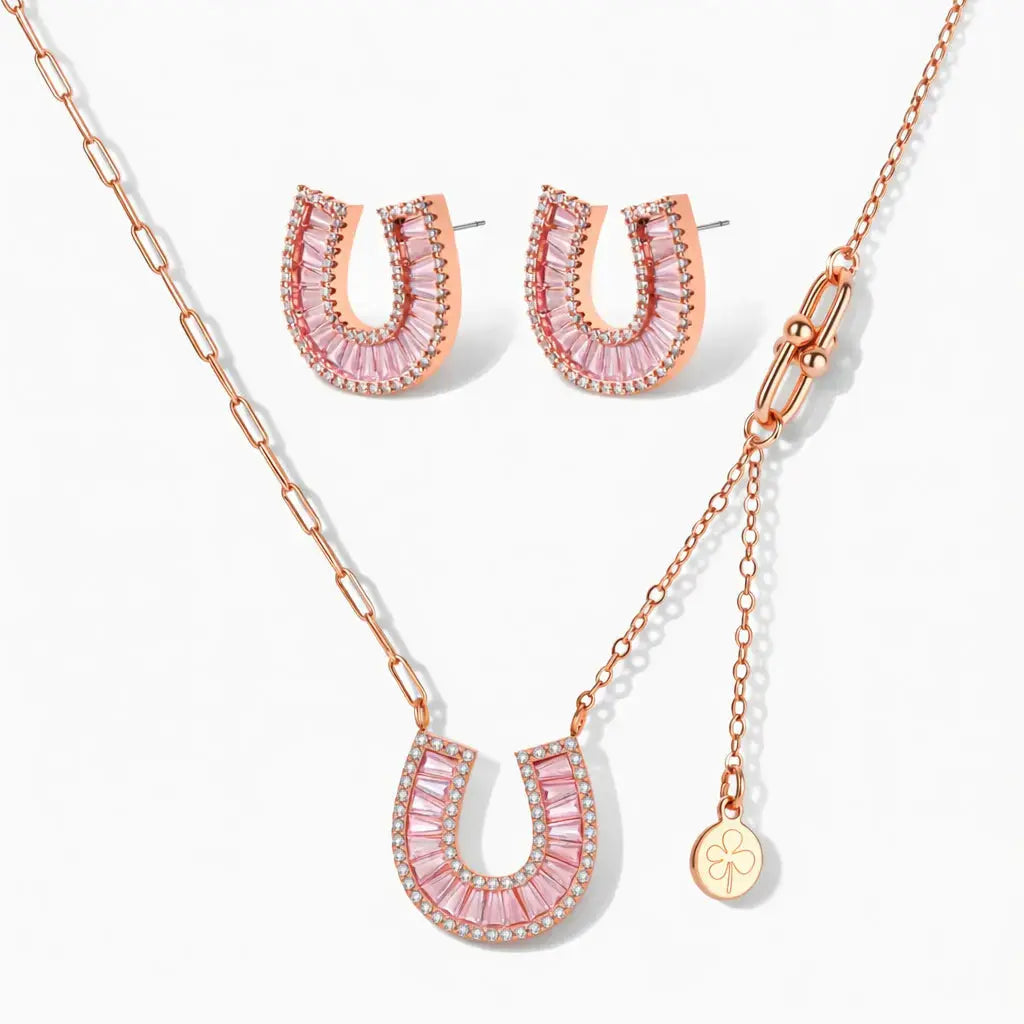 Rose gold horseshoe necklace and earrings set with pink and clear stones on white background