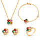 A gold jewelry set featuring a necklace, bracelet, earrings, and ring, each with a four-petal flower design set with red, green, pink, and yellow gemstones and small clear stones.