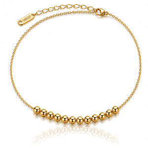 A delicate gold chain anklet featuring a row of polished gold beads along the bottom curve, with an adjustable lobster clasp and extender chain marked '18KGP'.