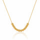 A gold beaded necklace with a curved row of polished spherical beads on a delicate chain, displayed against a clean white background with a soft reflection below.