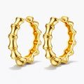 Pair of gold bamboo-style hoop earrings on a white background