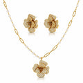 Gold-tone floral jewelry set with a pendant necklace, matching stud earrings, and a chain featuring small white pearls, shown on a clean white background.