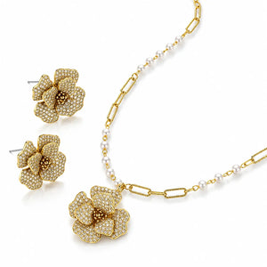 Gold jewelry set featuring a necklace and matching earrings with flower-shaped pavé settings and a section of white pearl chain, shown on a white background.