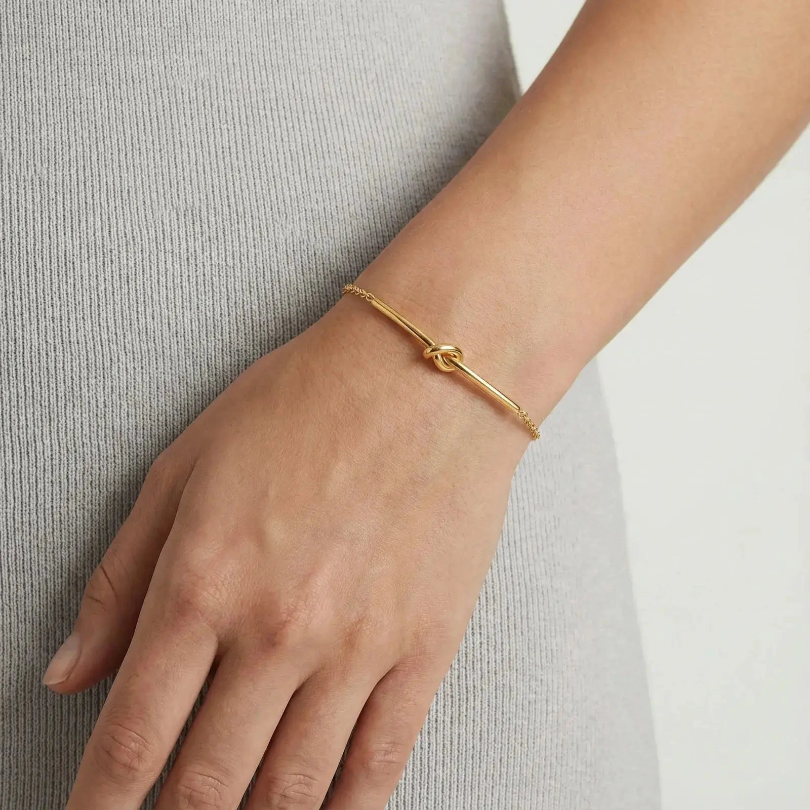 Gold knot bar bracelet on wrist, delicate chain, minimalist jewelry style