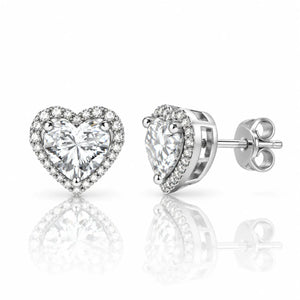 A pair of heart-shaped stud earrings featuring a large clear heart-cut center stone surrounded by a halo of smaller clear stones, shown on a white background with one earring facing forward and the other at an angle showing the post and backing.