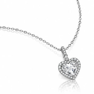 A silver heart-shaped pendant necklace with a halo of small clear stones surrounding a larger central clear heart-shaped stone, shown on a white background with a soft reflection.