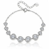 A silver-tone chain bracelet featuring seven heart-shaped settings, each adorned with clear stones, displayed on a clean white background with a soft reflection.