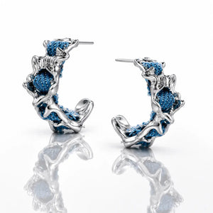 Pair of silver hoop earrings with blue thread on a white background