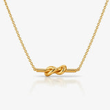 Gold necklace with a knot design on a white background
