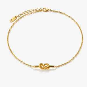 Gold bracelet with a knot design on a white background