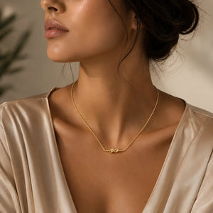 Close-up of a woman wearing a gold necklace with a neutral background