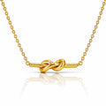 A gold necklace with a polished knot pendant on a fine link chain, displayed against a clean white background with a soft reflection below.
