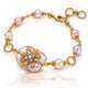 A gold chain bracelet featuring baroque-style pinkish pearl beads and a large central iridescent pearl pendant with a gold floral filigree setting and small clear stones, shown on a white reflective background.