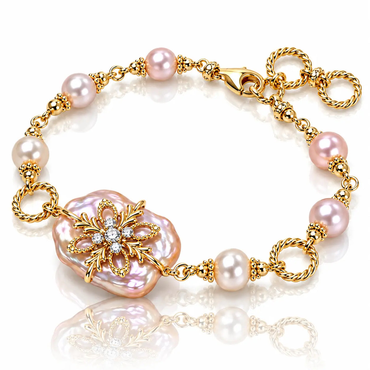 A gold-plated bracelet featuring pink freshwater pearls, a large baroque pearl centerpiece, and a gold floral brooch with clear rhinestones, shown on a reflective white background.