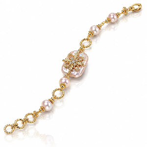 A gold chain bracelet featuring a large baroque pearl at the center, accented by smaller round pearls and twisted gold links, displayed on a clean white background.