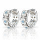 A pair of silver huggie hoop earrings decorated with white mother-of-pearl flower petals, clear rhinestones, and light blue oval center stones, displayed on a reflective white surface.