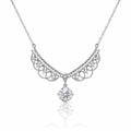 A silver-toned necklace featuring an ornate filigree crescent pendant adorned with small clear stones and a dangling round-cut clear gemstone, shown on a white background with a soft reflection below.
