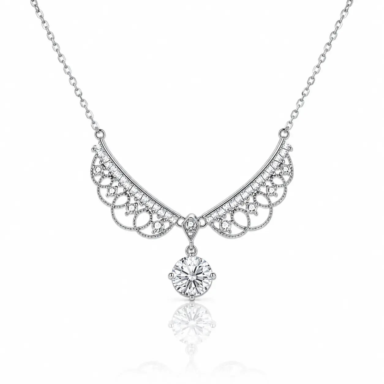 A silver-toned necklace featuring an ornate filigree crescent pendant adorned with small clear stones and a dangling round-cut clear gemstone, shown on a white background with a soft reflection below.