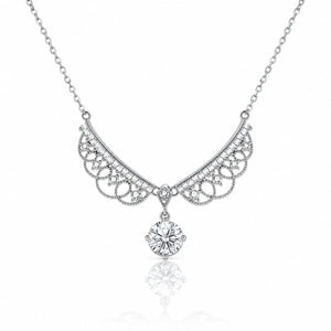 A silver-toned necklace featuring an ornate filigree crescent pendant adorned with small clear stones and a dangling round-cut clear gemstone, shown on a white background with a soft reflection below.