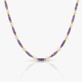 Necklace with purple, gold, and white beads on a white background