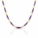 A beaded necklace featuring alternating strands of faceted purple amethyst beads, white freshwater pearls, and polished gold spacer beads, displayed on a clean white background with a soft reflection.