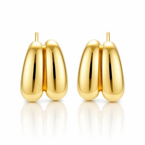 A pair of polished gold hoop earrings with a rounded, organic double-lobed design, displayed on a clean white background with soft reflections below.