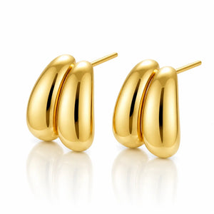 A pair of polished gold hoop earrings with a rounded, three-bar design, displayed on a clean white background with soft reflections below.