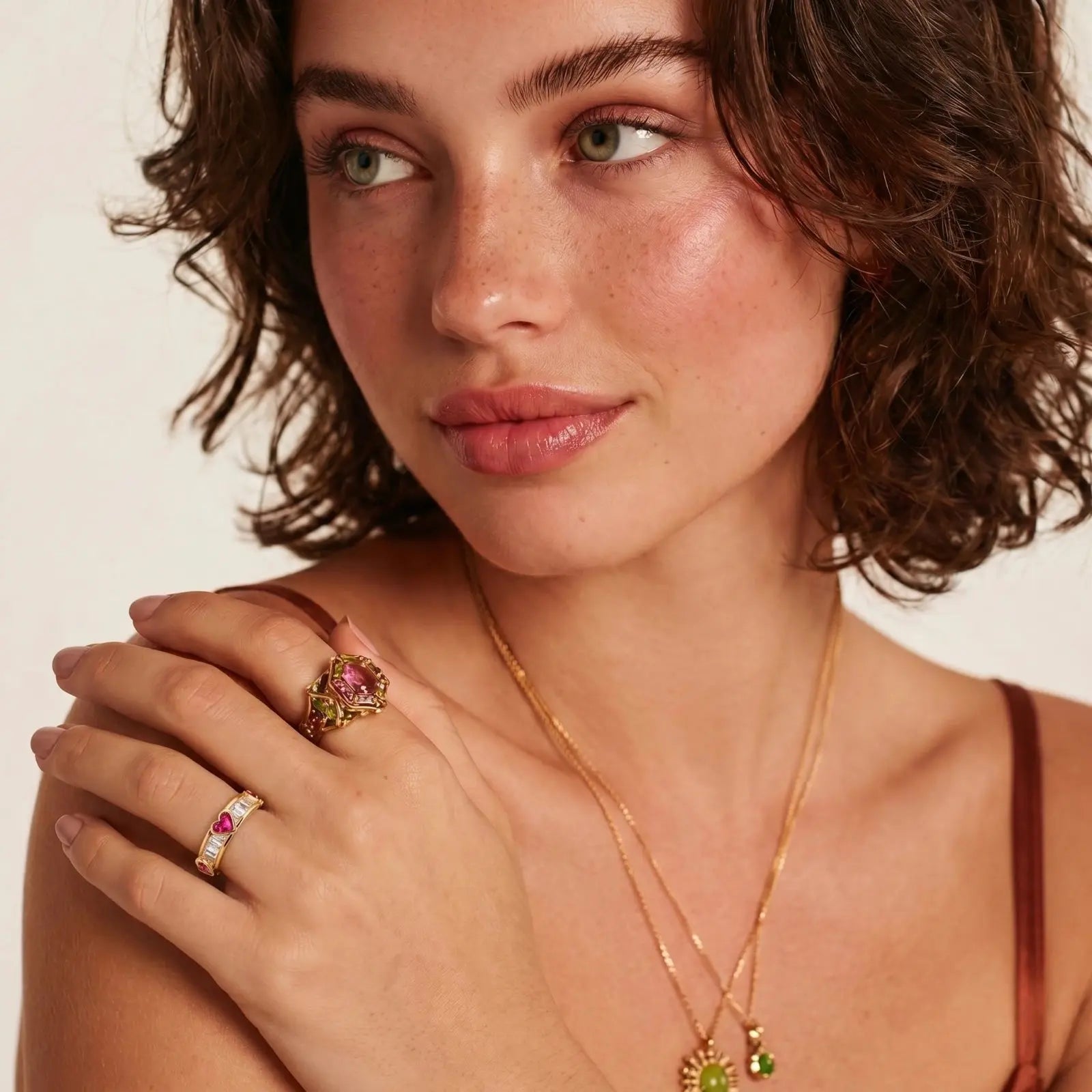 Woman wearing gold jewelry with a neutral background